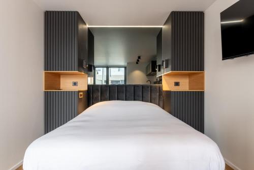 a bedroom with a white bed and a tv at Studios Le Médicis in Rouen