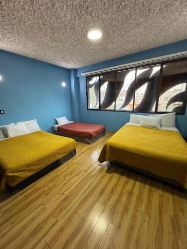two beds in a room with blue walls and wooden floors at Gran México in Mexico City