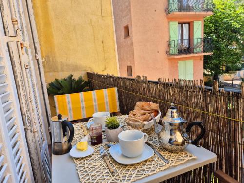 - un balcon avec une table et un service à thé dans l'établissement Carolina, T3 centre historique de Bandol, à Bandol