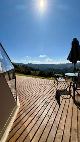 a wooden deck with a table and a chair on it at Montanha Home in Monte Verde
