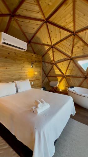a bedroom with a white bed with a bath tub at Montanha Home in Monte Verde