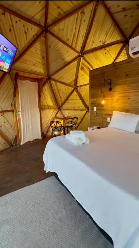 a bedroom with a white bed in a wooden room at Montanha Home in Monte Verde