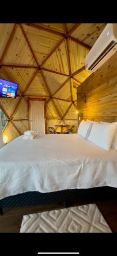 a bedroom with a white bed in a wooden ceiling at Montanha Home in Monte Verde