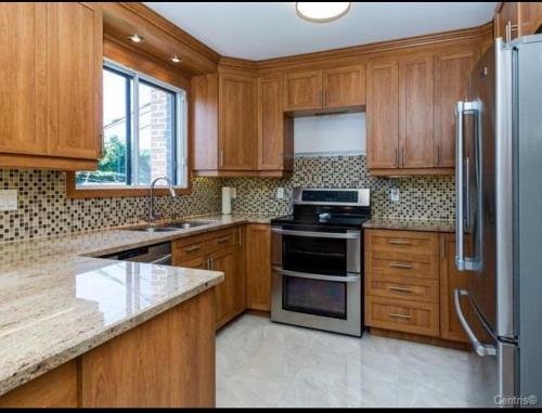 a kitchen with wooden cabinets and stainless steel appliances at Spacious 4-Bdr Retreat in Charming Ste-Rose, Laval in Laval