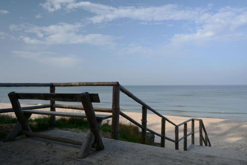 a bench sitting on the beach near the ocean at Willa Victor in Jastrzębia Góra