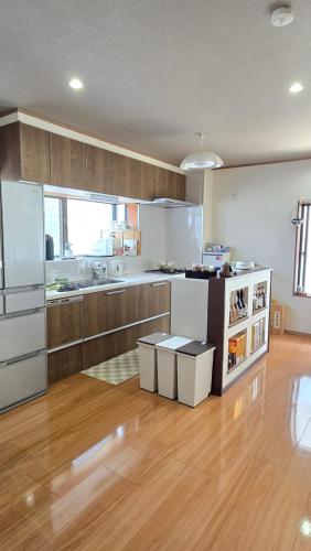 a kitchen with white appliances and wooden floors at 海の風 in Wakayama