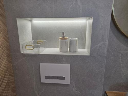 a bathroom with two white bottles on a shelf at Apartament Kwiatowy DeLux in Sanok