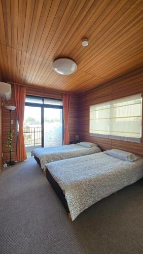 three beds in a room with a wooden ceiling at 海の風 in Wakayama