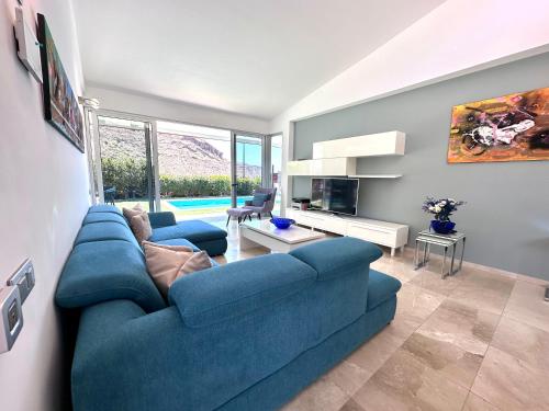a living room with a blue couch and a tv at Estrella Del Sur Tauro Ocean Wiew Heated Pool in Mogán
