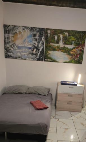une chambre avec un lit avec trois tableaux au mur dans l'établissement Charmant appartement ensoleillé à deux pas de Monaco, à Beausoleil
