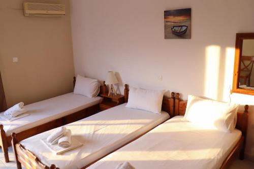 three beds in a room with white sheets at Themis - Θέμις Apart Hotel in Loutra Edipsou