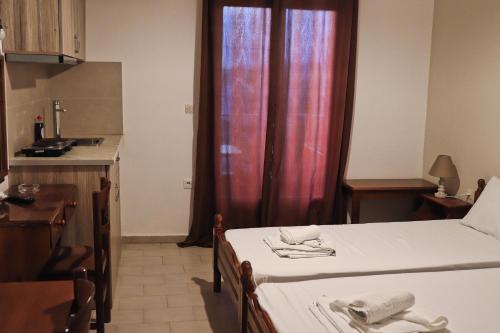 a room with two beds and a kitchen with a window at Themis - Θέμις Apart Hotel in Loutra Edipsou