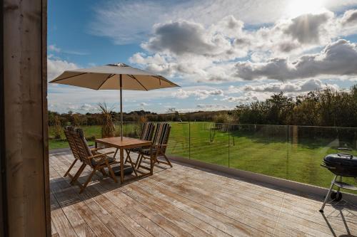 a patio with a table and chairs and an umbrella at Willow Lodge in Six Road Ends