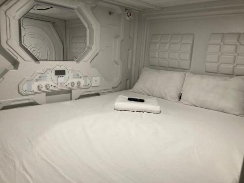 a white bed with a remote control sitting on it at Green Caps in Cancún