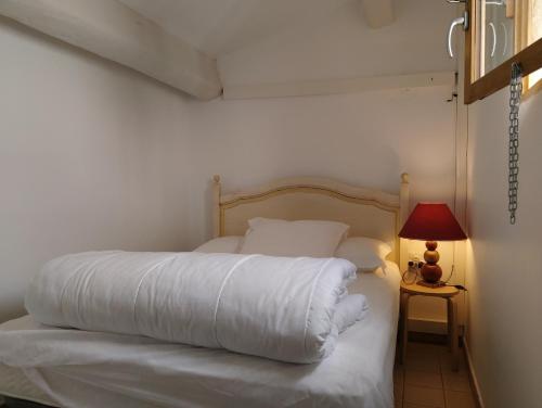 une chambre avec un lit avec des draps blancs et une lampe dans l'établissement La mouette rieuse, à Saintes-Maries-de-la-Mer
