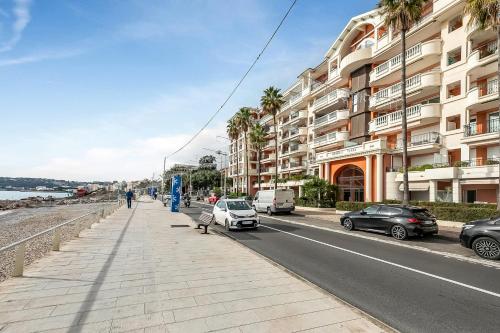 un trottoir avec des voitures garées sur le côté d'une rue dans l'établissement Admiral Plaza Sea View - Happy Rentals, à Menton
