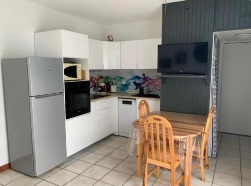 une cuisine avec une table, des chaises et un réfrigérateur dans l'établissement Plage Le Lydia, au Barcarès
