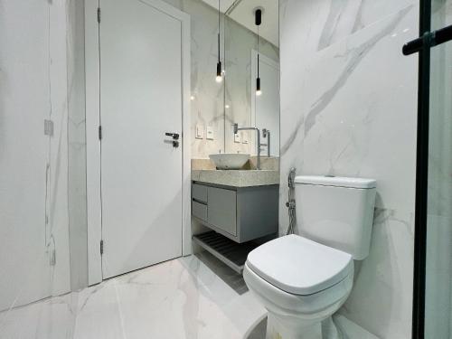 a white bathroom with a toilet and a sink at Estúdios modernos no City House by WeHousy in Barreiras