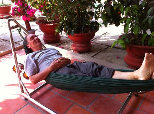 a man laying in a hammock on a patio at Sao Mai Hotel in Cai Be