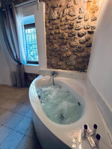 a bath tub in a room with a stone wall at Agriturismo Masseria Pozzo in Sperlonga