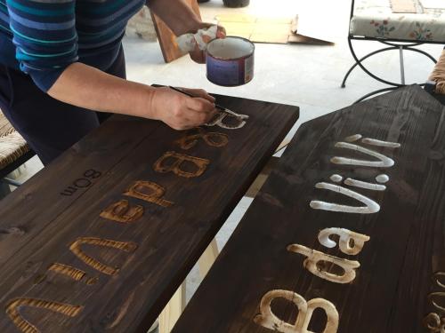 a person writing on a wooden table with glasses on it at B&B da Vi.Vì in Urbania