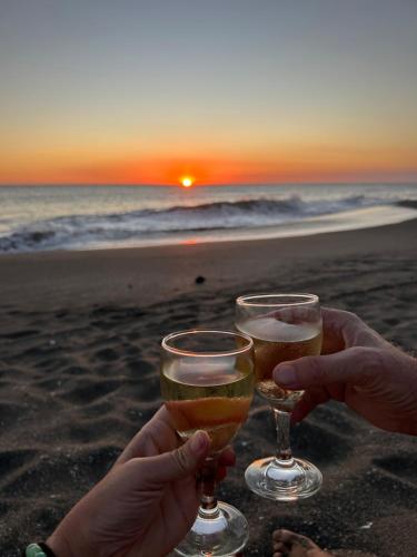 two people holding glasses of beer on the beach at Hotel Tranquilo in Las Peñitas