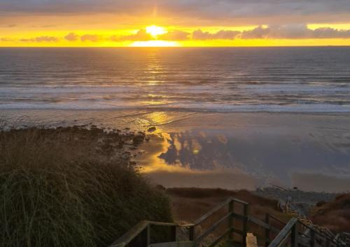 a sunset over the ocean with the sun setting at Mobil-home Vue mer Piscine - Camping La Falaise Equihen-Plage - La Coquille d'Opale in Équihen-Plage