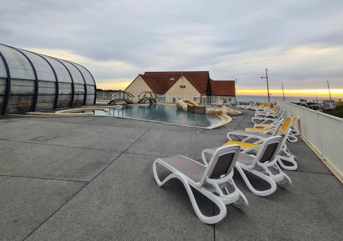 a row of chairs sitting on a roof with a pool at Mobil-home Vue mer Piscine - Camping La Falaise Equihen-Plage - La Coquille d'Opale in Équihen-Plage