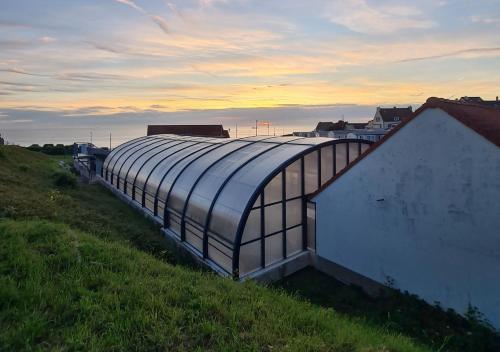 a large glass building on top of a hill at Mobil-home Vue mer Piscine - Camping La Falaise Equihen-Plage - La Coquille d'Opale in Équihen-Plage