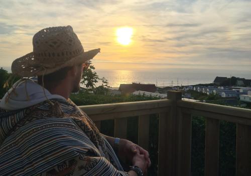 a man sitting on a balcony watching the sunset at Mobil-home Vue mer Piscine - Camping La Falaise Equihen-Plage - La Coquille d'Opale in Équihen-Plage