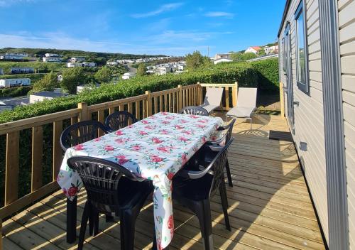 a table and chairs on a deck with a table and a tablecloth at Mobil-home Vue mer Piscine - Camping La Falaise Equihen-Plage - La Coquille d'Opale in Équihen-Plage