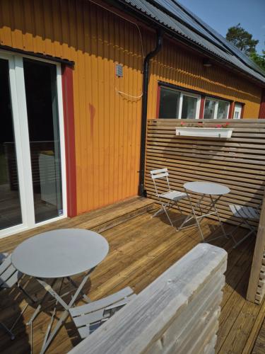 two tables and chairs on a deck next to a building at Country Lodge Lärkboet in Laholm