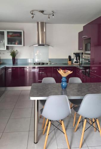 une cuisine avec des placards violets, une table et des chaises dans l'établissement La Maison de Cathy, à Pérols