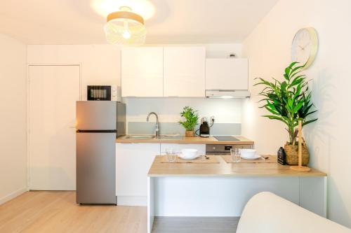 a kitchen with white cabinets and a stainless steel refrigerator at Le Carré CDG Studio Élégant in Gonesse