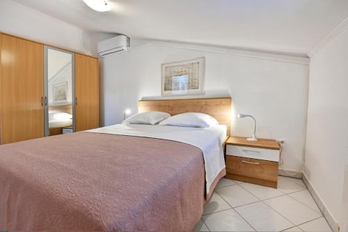 a bedroom with a large bed and a lamp on a night stand at Apartments Pilic in Rošini