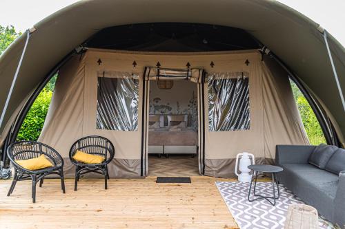 a tent with a couch and chairs and a bed at Luxe Glamping Lodge Dahlia in Meerssen