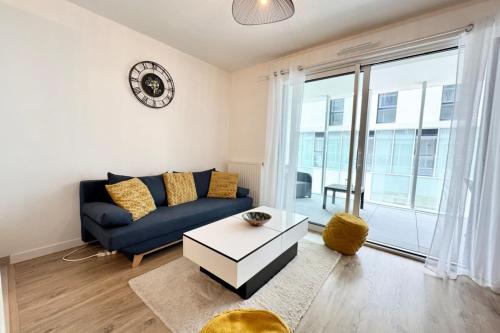 un salon avec un canapé bleu et une grande fenêtre dans l'établissement Péristyle - T2 de standing neuf - Balcon, à Lorient