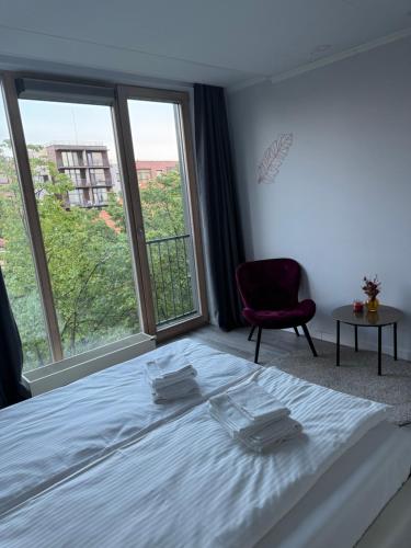 a bedroom with a bed and a chair and windows at MANTO NAMAI apartment in the center of Klaipeda with a view in Klaipėda