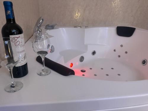 a white bath tub with a bottle of wine and two glasses at Secret Spa Nis in Niš