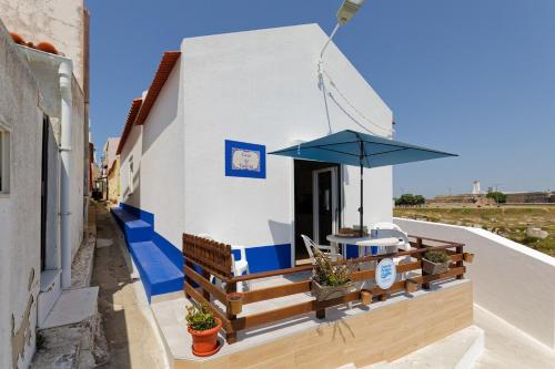 a house with a balcony with a blue umbrella at CASA DA FALÉSIA 28 - Casa in Peniche