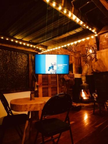 a living room with a table and a large screen at Cabaña en la Calera Cerezos in La Calera