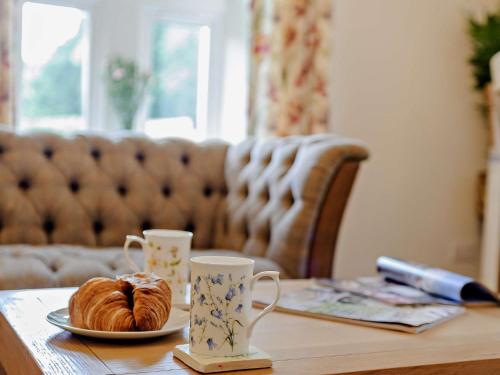 a table with a plate of croissants and two cups at 2 Bed in Hawick 91905 in Roberton