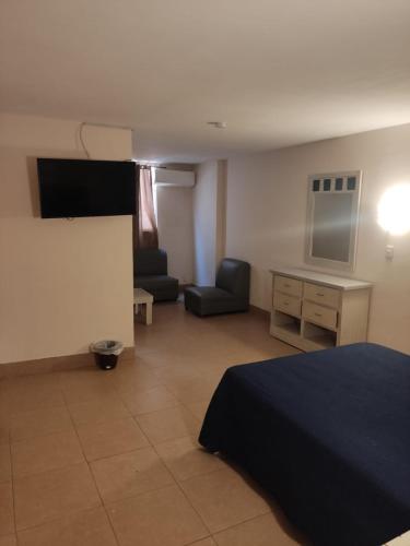 a room with a bed and a couch and a tv at Hotel del Paseo in Torreón