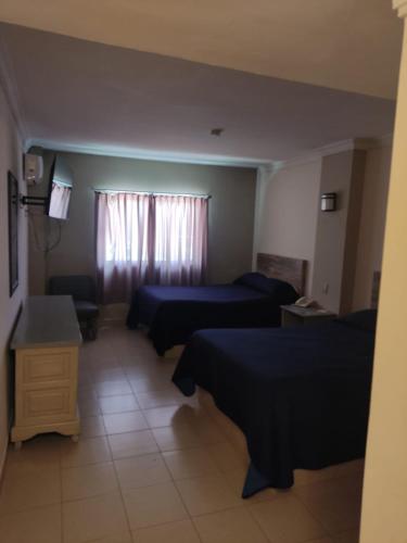 a hotel room with two beds and a couch at Hotel del Paseo in Torreón