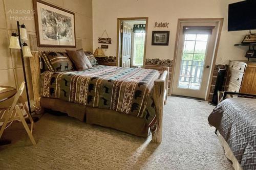 a bedroom with a bed and a table and a door at Alaska's Harvest Bed and Breakfast and Luxury Log Cabin in Palmer