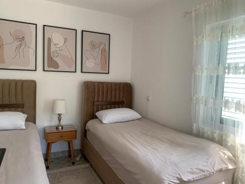 two beds in a bedroom with pictures on the wall at Apartment Dream Summer 2 -Premium Beach Apartament for 4 in Tivat