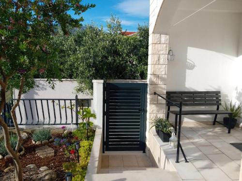 a garden with a black door and a bench at Guesthouse Korkyra Sun in Korčula