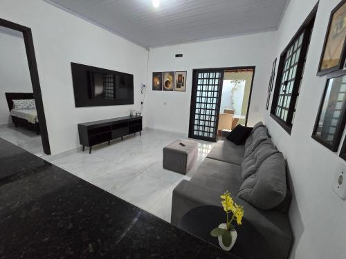 a living room with a couch and a television at Casa completa dois quartos, com ar condicionado, churrasqueira, garagem in Aparecida de Goiania