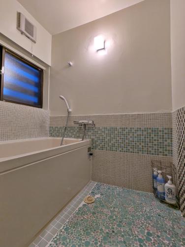 a bathroom with a tub and a tile floor at Tsugaru House1 in Aomori