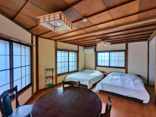 a room with two beds and a table in it at Tsugaru House1 in Aomori